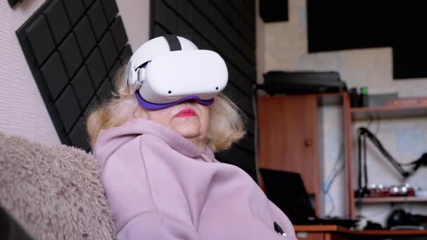 Mulher Surpresa Sentada Sofá Capacete Com Óculos Realidade Virtual Idosa — Vídeo de Stock