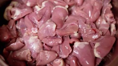 Kadın eli taze soyulmuş tavuk kalplerini tabakta karıştırıyor. Yakın plan. Parlak kırmızı tavuk kalbi, ikiye bölünmüş. Beslenme eti. İkinci sınıfın yan ürünleri. Fakirler için ucuz yemek. 4K.