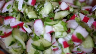 Şef Stirring yanında taze sebze salatası, turp, salatalık, yeşillik. Yakın plan. Renkli yeşil soğan, maydanoz, turp ve salatalık sebzesi karışımı, yağ. Vejetaryen diyeti. Sağlıklı yemek..