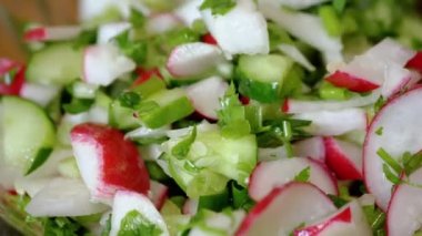 Şef Stirring yanında taze sebze salatası, turp, salatalık, yeşillik. Yakın plan. Renkli yeşil soğan, maydanoz, turp ve salatalık sebzesi karışımı, yağ. Vejetaryen diyeti. Sağlıklı yemek..