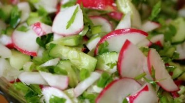 Şef Stirring yanında taze sebze salatası, turp, salatalık, yeşillik. Yakın plan. Renkli yeşil soğan, maydanoz, turp ve salatalık sebzesi karışımı, yağ. Vejetaryen diyeti. Sağlıklı yemek..