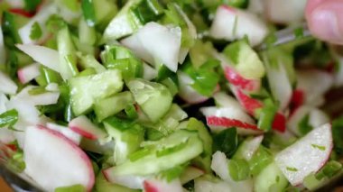 Şef Stirring yanında taze sebze salatası, turp, salatalık, yeşillik. Yakın plan. Renkli yeşil soğan, maydanoz, turp ve salatalık sebzesi karışımı, yağ. Vejetaryen diyeti. Sağlıklı yemek..
