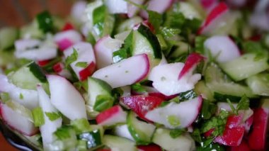 Şef Stirring yanında taze sebze salatası, turp, salatalık, yeşillik. Yakın plan. Renkli yeşil soğan, maydanoz, turp ve salatalık sebzesi karışımı, yağ. Vejetaryen diyeti. Sağlıklı yemek..