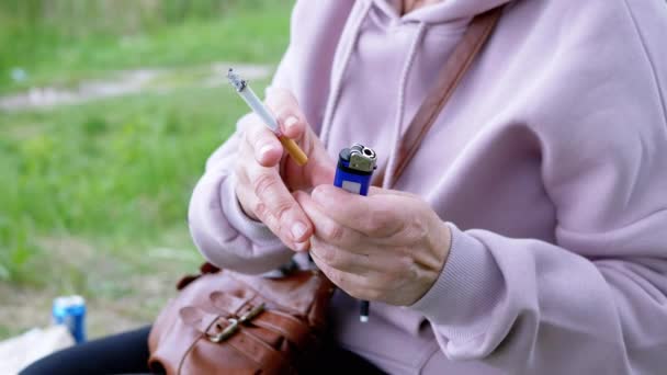 Γυναίκα Κρατώντας Ένα Τσιγάρο Και Ένα Αναπτήρα Στα Χέρια Κάθεται — Αρχείο Βίντεο