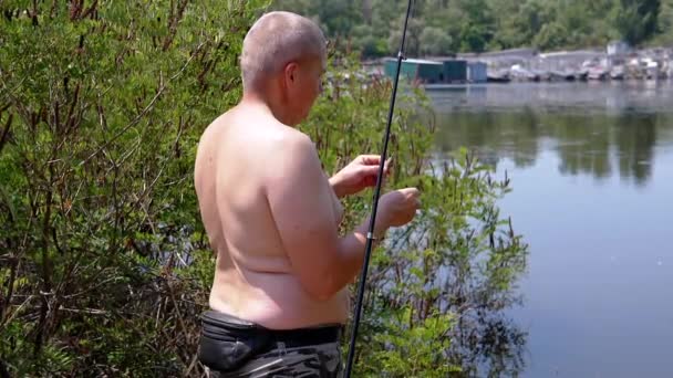 渔夫在钓钩上放磁铁 在自然条件下捕捞饲料 日落时分 一个赤身裸体的男人和一根钓竿在河边的阳光下钓鱼 — 图库视频影像