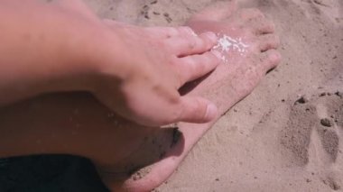 Kadın eli, bronzlaşmış kırmızı bacak derisine güneş kremi sürüp sürtünüyor. Güneş yanığı kremi. Güvenli bronzlaşma ve plajda güneşli bir yaz gününde bir çocuğun cilt bakımı. Gün batımında güneş ışığı. Dinlen, hafta sonu.