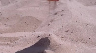 Kadın El, Güneş Işığındaki Sahilde Kumu Parmaklarından Döker. İnce kum taneleri güneşin altındaki sıcak altın kumun üzerine yavaşça düşer gün batımında parlar. Deniz kıyısında dinlenmek, deniz kıyısında bir tatil köyü..