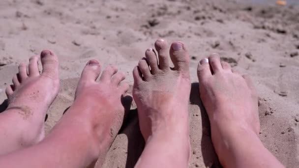 在沙滩上的沙滩上 母亲和孩子赤裸裸的赤脚躺在沙滩上 人们在炎热的阳光下移动脚趾 腿在阳光下晒日光浴 家庭放松 度假胜地 — 图库视频影像