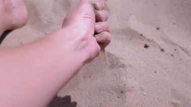 Kadın El, Güneş Işığındaki Sahilde Kumu Parmaklarından Döker. İnce kum taneleri güneşin altındaki sıcak altın kumun üzerine yavaşça düşer gün batımında parlar. Deniz kıyısında dinlenmek, deniz kıyısında bir tatil köyü..