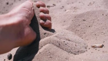 Kadın El, Güneş Işığındaki Sahilde Kumu Parmaklarından Döker. İnce kum taneleri güneşin altındaki sıcak altın kumun üzerine yavaşça düşer gün batımında parlar. Deniz kıyısında dinlenmek, deniz kıyısında bir tatil köyü..