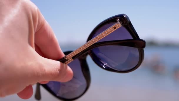 Female Hand Holding Dark Sunglasses Backdrop Seascape Girl Enjoying Relaxing — Stockvideo