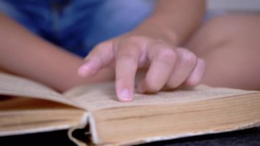 Çocuk, Parmaklarını Kitap ve Okuma Sayfası boyunca hızla koşar. Evde Uzaktan Okuma. Kendini soyutlama. Online eğitim. İnternet olmadan karantinada yeni bilgiler. Metnin bağımsız çalışması. Öğrenme.