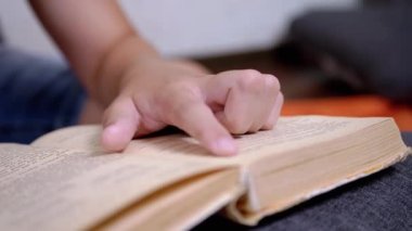 Çocuk, Parmaklarını Kitap ve Okuma Sayfası boyunca hızla koşar. Evde Uzaktan Okuma. Kendini soyutlama. Online eğitim. İnternet olmadan karantinada yeni bilgiler. Metnin bağımsız çalışması. Öğrenme.