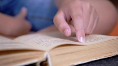 Çocuk, Parmaklarını Kitap ve Okuma Sayfası boyunca hızla koşar. Evde Uzaktan Okuma. Kendini soyutlama. Online eğitim. İnternet olmadan karantinada yeni bilgiler. Metnin bağımsız çalışması. Öğrenme.