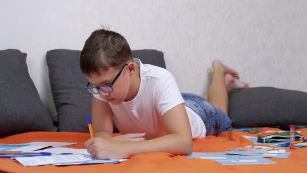 Defterinde Kalemle Yazan Çocuk Odadaki Portakal Yatak Örtüsü Üzerinde Yatan — Stok video