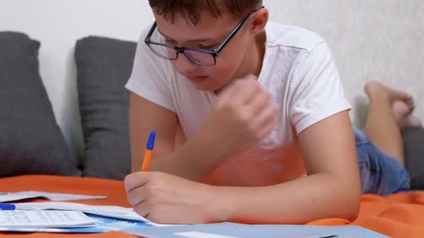 Kind Schreibt Mit Stift Notizbuch Auf Orangefarbener Bettdecke Zimmer Liegend — Stockvideo