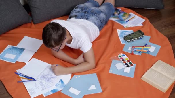 Child Writing Pen Notebook Lying Orange Bedspread Room Serious Sad — Videoclip de stoc