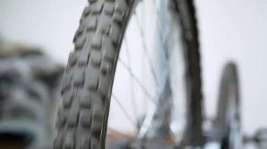 Rotation of a Black Rubber Bicycle Wheel with Spokes in the Workshop. Checking the wheel for punctures, cracks, and damage. Close-up. Spinning wheel testing. Concept of repair, travel. Slow-motion.