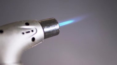 Siyah Arkaplanda Taşınabilir Gaz Yakma Makinesinde Erkek El Tutma. Yakın plan. Elle yakılan küçük kaynak makinesi, silaha benzer bir yakıcı parlak mavi alevle parlar. Yakıcı, barbekü tabancası. Yavaş çekim.