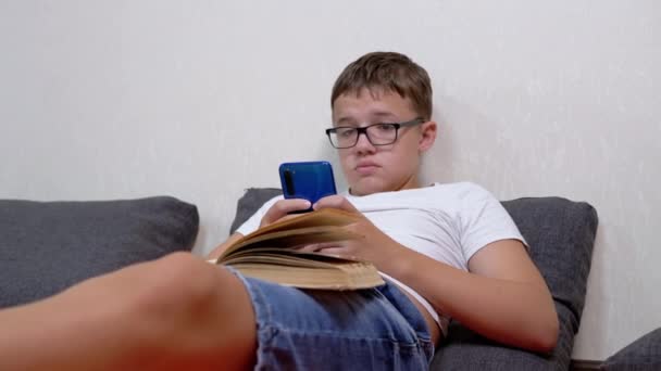 Teen Glasses Smartphone Hands Open Book Studying Online Home Σοβαρός — Αρχείο Βίντεο