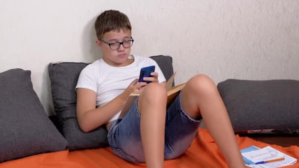 Teen Glasses Smartphone Hands Open Book Studying Online Home Έξυπνο — Αρχείο Βίντεο