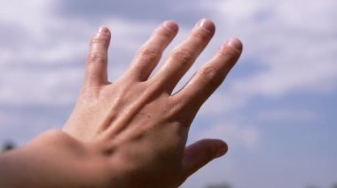 Female Hand Reaching for the Sky, to Sun on Nature. Colorful nature, white clouds, outdoors. Hope, dream of a journey. Sunlight, rays. Sun glare. Hope, request. Restoration of strength. Summertime.
