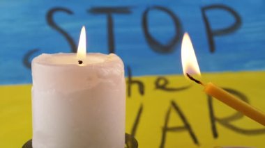Two Burning Candles on the Background of the Yellow Blue Flag of Ukraine. Prayer. Inscription Stop the war on national flag, poster. Drawing. Memory of the victims of the war, died soldiers in battle.