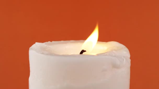 在一个孤立的橙色背景上 燃烧着一个明亮的火焰的白色蜡烛 黄色移动的火 记忆的概念 摘要背景 慢动作 — 图库视频影像
