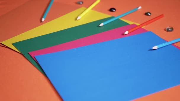 Veelkleurige Vellen Kartonnen Papier Een Oranje Tafel Achtergrond Schoolbenodigdheden Potloden — Stockvideo