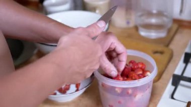 Male Hands Cutting Strawberries with a Knife and Putting them in a Deep Bowl. Time lapse. Preparing a healthy dessert from fresh berries at home in kitchen. Harvest. Organic seasonal food. Vitamins.