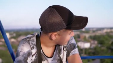 Smiling Boy Enjoying Panoramic View of the City from the Cabin of a Ferris Wheel. Happy child is worried, looking from a height at the sky, around, examining the surroundings, scenery. Amusement park.