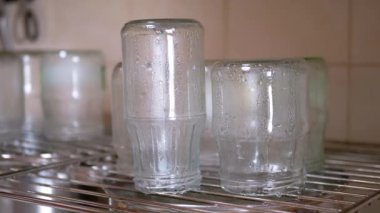 Sterilization of Glass Jars with Hot Steam on a Metal Grate at Home in Kitchen. Drops of water flowing down. Process of preparing glass containers for the preservation of vegetables for the winter.