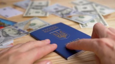 Ukrayna 'nın Biyometrik Pasaportunu Dökülen Parayla Masada Açan Eller. Ukraynaca yazı: Ukrayna pasaportu. Pasaport alıyorum. Savaş konsepti, seyahat, Rus saldırısı, mülteci, göçmen.