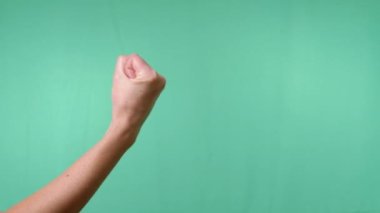 Boş Yeşil Krom Anahtar Arkaplan 'da Yumruk' a sıkıştı. Dişi el, parmaklarını yumruğa sıkıyor. Tehdit edici jest, güç, saldırganlık. Vücut dili, vücut dili. Çakışma.