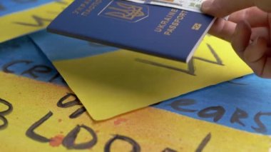 Hand, Ukrayna 'nın Biyometrik Pasaportunu Nakitle Bayrakların Arkasında Bırakıyor. Ukrayna Ukrayna pasaportuyla yazılmış. Sarı, mavi Ukrayna bayrağı çizimleri. Başlığı 