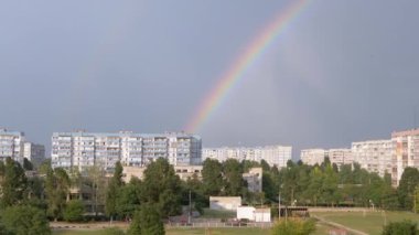 Gökyüzünde çok renkli Parlak Gökkuşağı Çatı Modern Binaları 'nda. Şehrin üzerine yağan kör bir yaz yağmurundan sonra kocaman güzel bir gökkuşağı parlıyor. Ufuk çizgisinde güzel bir doğa olayı.