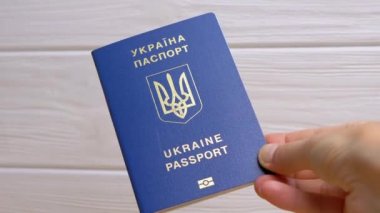 Beyaz Arkaplanda Ukrayna 'nın Mavi Biyometrik Pasaportunu Tutan Kadın Eli. Ukrayna Ukrayna pasaportuyla yazılmış. Kız yurtdışına seyahat ve seyahat için verilen uluslararası belgeyi gösteriyor.