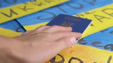 Hand, Ukrayna 'nın Biyometrik Pasaportunu Bayrakların Arkasındaki Masadan Aldı. Sarı, mavi Ukrayna bayrağı çizerek savaşı durdurun. Savaş, ülkeyi terk eden göçmenler, Rus saldırısı.