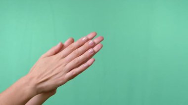 Boş Yeşil Krom Anahtar Arkaplanına Elleri Sürten Kadın. Bekleme anı, el masajı, ısınma, cilt okşama, el yıkama. El hareketleriyle. Uzay reklam arkaplanını kopyala. Yakın plan..