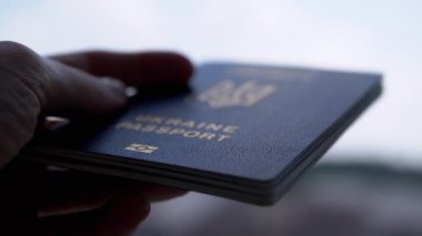 Ukrayna Havaalanı 'nda Mavi Gök' e karşı Biyometrik Pasaport tutuyor. El silueti yakın plan. Yurtdışına seyahat için belge. Savaş, seyahat, mülteci, göçmen, seyahat, tatil kavramı.