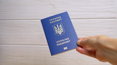 Beyaz Arkaplanda Ukrayna 'nın Mavi Biyometrik Pasaportunu Tutan Kadın Eli. Ukrayna Ukrayna pasaportuyla yazılmış. Kız yurtdışına seyahat ve seyahat için verilen uluslararası belgeyi gösteriyor.