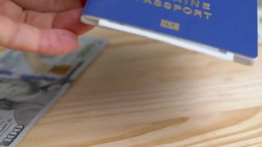 Tahta Masaya 100 Dolarlık banknotla Ukrayna Biyometrik Pasaportu Veriliyor. Dağınık para, masada plastik kartlar. Mültecilerin, göçmenlerin yurt dışına çıkışı. Savaş, seyahat, seyahat, Rus saldırısı.