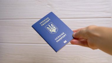 Beyaz Arkaplanda Ukrayna 'nın Mavi Biyometrik Pasaportunu Tutan Kadın Eli. Ukrayna Ukrayna pasaportuyla yazılmış. Kız yurtdışına seyahat ve seyahat için verilen uluslararası belgeyi gösteriyor.