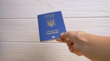 Beyaz Arkaplanda Ukrayna 'nın Mavi Biyometrik Pasaportunu Tutan Kadın Eli. Ukrayna Ukrayna pasaportuyla yazılmış. Kız yurtdışına seyahat ve seyahat için verilen uluslararası belgeyi gösteriyor.