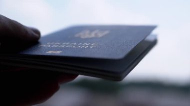 Ukrayna Havaalanı 'nda Mavi Gök' e karşı Biyometrik Pasaport tutuyor. El silueti yakın plan. Yurtdışına seyahat için belge. Savaş, seyahat, mülteci, göçmen, seyahat, tatil kavramı.