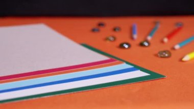 Female Hands Laying Multicolored Sheets of Cardboard on an Orange Background. Preparation of colored paper for the lesson. Learning colors, shapes for preschool kids. Rainbow. School. Education.