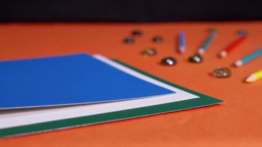 Female Hands Laying Multicolored Sheets of Cardboard on an Orange Background. Preparation of colored paper for the lesson. Learning colors, shapes for preschool kids. Rainbow. School. Education.