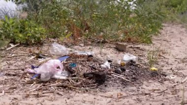 Discarded Garbage from Plastic Bottles, Plastic Bags in Sun in Forest on Sand. Garbage pit, dump, waste in nature in woods. A place for a campfire. Environmental pollution, environmental disaster.