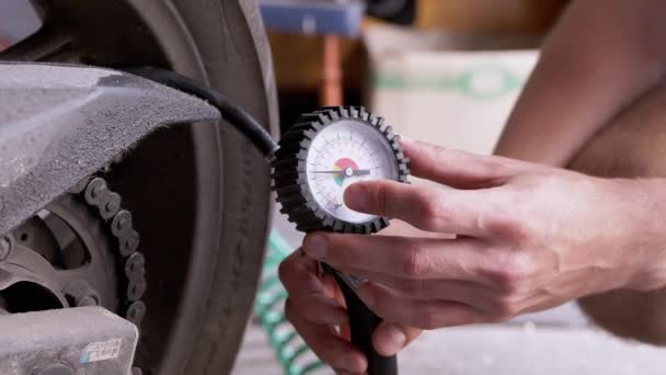 男性用压力表检查摩托车轮胎中的气压 压力计针头测量轮胎压力 车库里的司机在离开前要检查摩托车车轮的安全性 — 图库视频影像