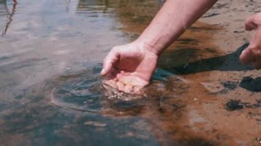 Male Hand Splashing in the Water, playing, creating Splashes in Sun at Sunset. Fingers touching surface of water. Drops are reflected in bright rays of sunlight. Concept of travel, enjoying nature.